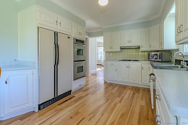 a kitchen with stainless steel appliances granite countertop a table chairs sink and cabinets