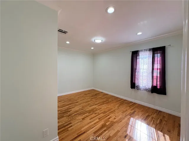 a view of an empty room with window and wooden floor