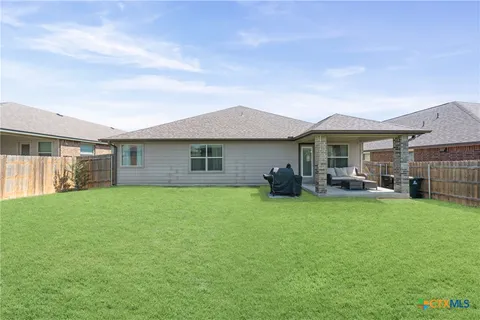 a view of a house with a patio and a yard