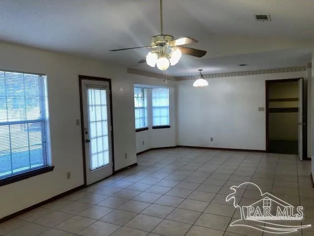 an empty room with windows and ceiling fan
