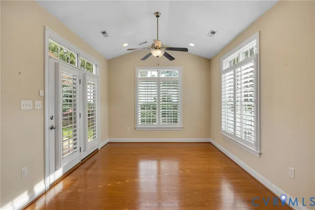 a view of a livingroom with furniture a fireplace wooden floor and windows