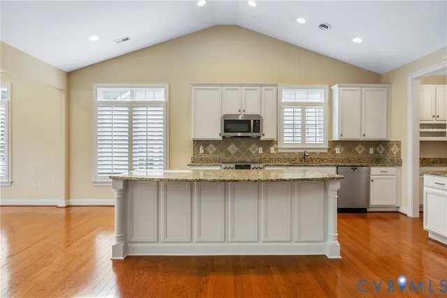 a kitchen with granite countertop white cabinets and stainless steel appliances