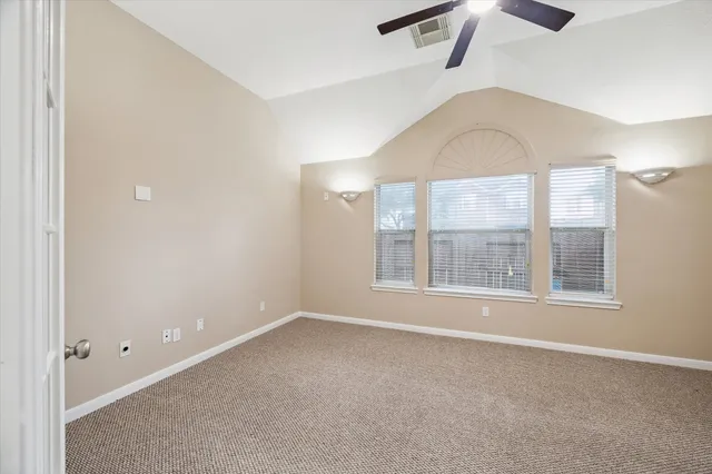an empty room with windows and ceiling fan