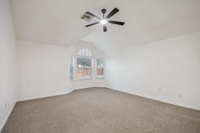 an empty room with ceiling fan and windows