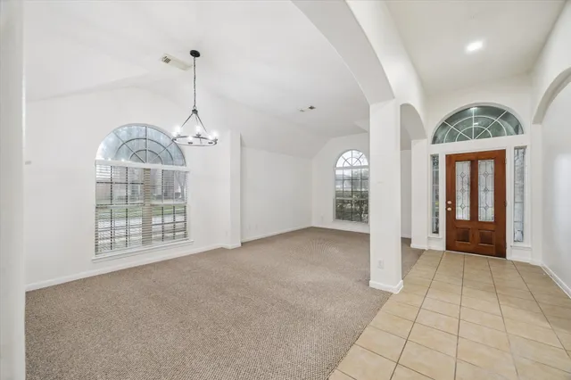 a view of an empty room with chandelier fan and windows