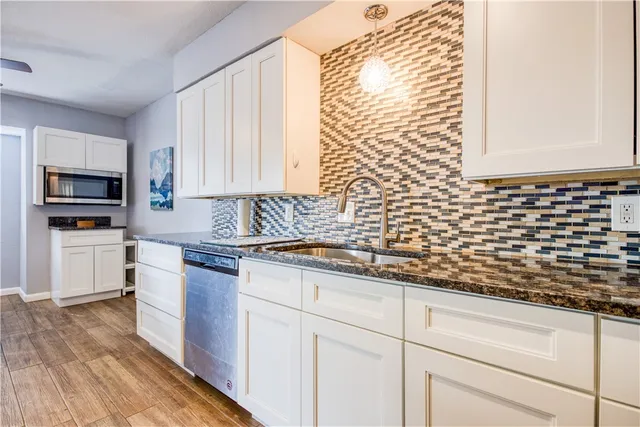 a kitchen with granite countertop white cabinets stainless steel appliances a sink and a window