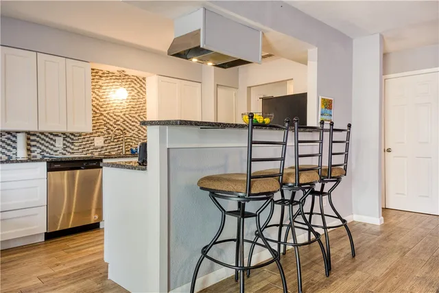 a kitchen with stainless steel appliances kitchen island granite countertop a table chairs in it and wooden floors