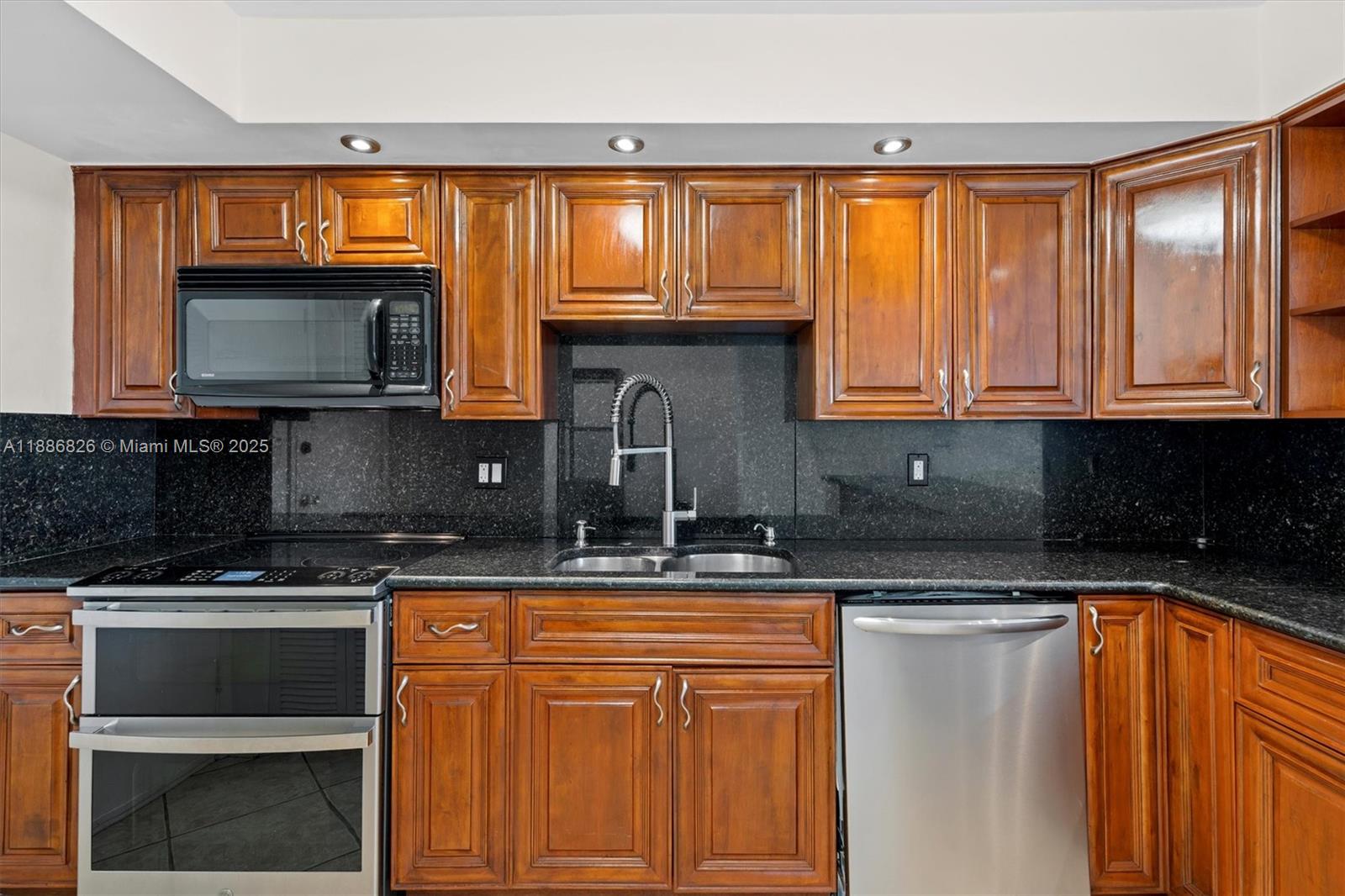 200 Diplomat Parkway, Unit 825 Hallandale Beach, FL 33009 - Photo 15 of 29 a kitchen with granite countertop stainless steel appliances a stove sink and microwave