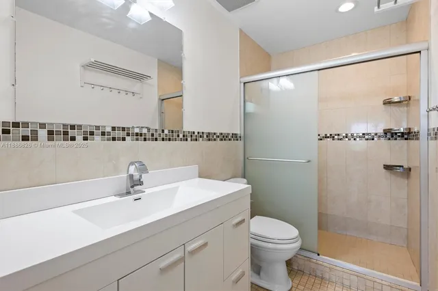 a bathroom with a sink a mirror a toilet and shower
