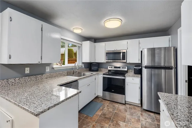 a kitchen with stainless steel appliances granite countertop a refrigerator stove microwave and sink