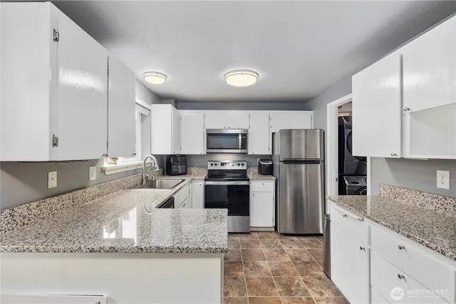 a kitchen with stainless steel appliances granite countertop a sink a stove top oven a refrigerator and dishwasher