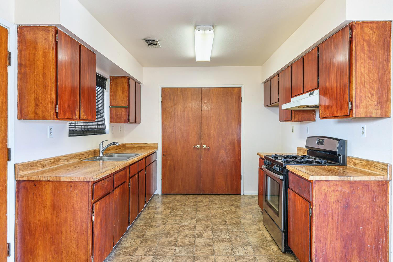 180 Monroe Street Coalinga, CA 93210 - Photo 19 of 25 a kitchen with stainless steel appliances granite countertop a stove a sink dishwasher and a refrigerator with wooden cabinets