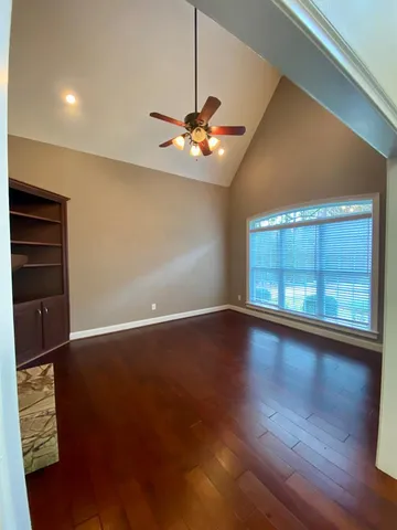 a view of an empty room with wooden floor and a window