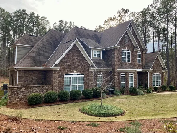 a view of a big house with a big yard and large trees