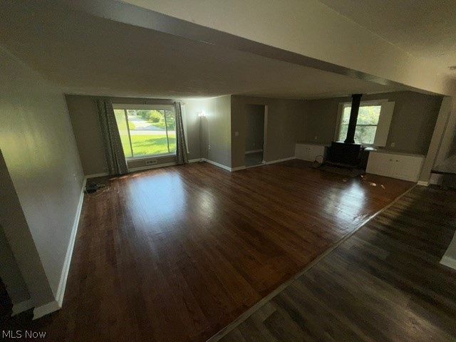 Spacious room featuring wood-finish flooring, a large window, a freestanding wood stove, and built-in cabinetry