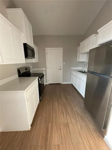 a kitchen with a sink a microwave a refrigerator and cabinets