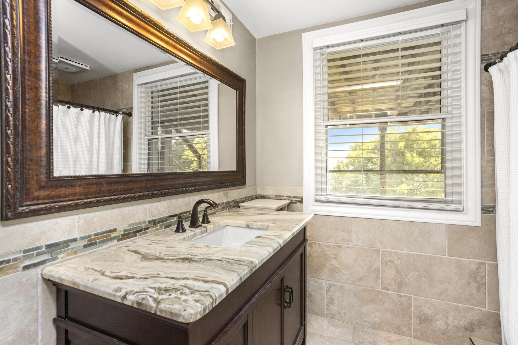 8733 Haselton Road Nashville, TN 37221 - Photo 24 of 28 a bathroom with a granite countertop sink and a window