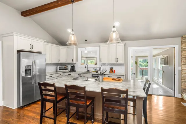 a kitchen with stainless steel appliances a dining table chairs refrigerator and microwave
