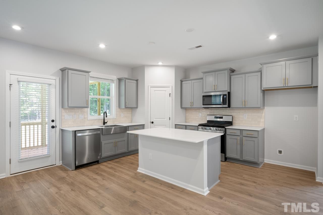 289 Madden Rose Loop Garner, NC 27529 - Photo 2 of 2 a kitchen with stainless steel appliances granite countertop a stove top oven a sink dishwasher a refrigerator and white cabinets with wooden floor