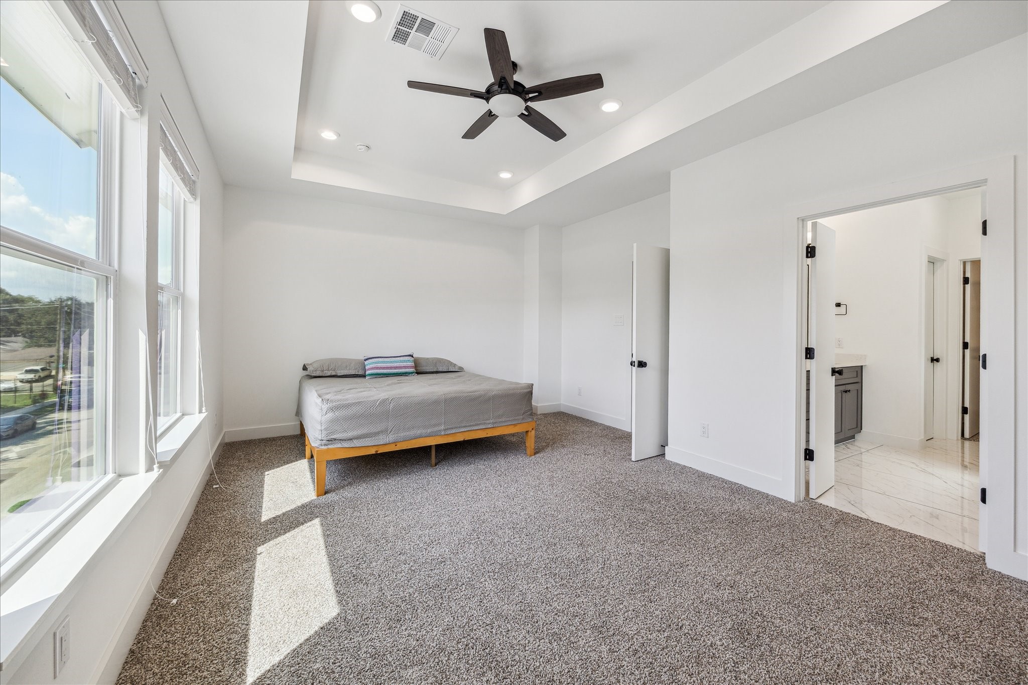 4854 Brinkman Street Houston, TX 77018 - Photo 11 of 30 Inviting primary retreat with oversized windows, modern ceiling fan, and a tray ceiling that adds architectural elegance.