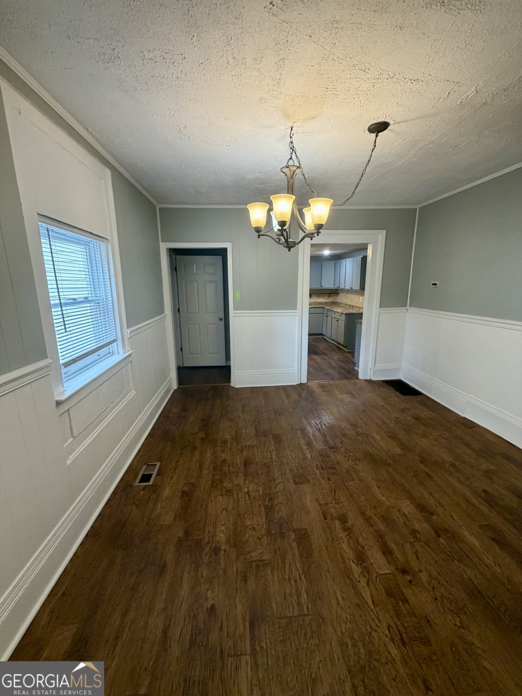 666 Woolfolk Street Macon, GA 31217 - Photo 15 of 60 an empty room with wooden floor chandelier and windows