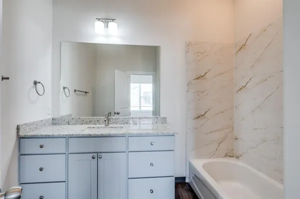 a bathroom with a granite countertop sink mirror and a bathtub