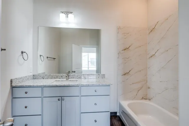 a bathroom with a granite countertop sink mirror and a bathtub