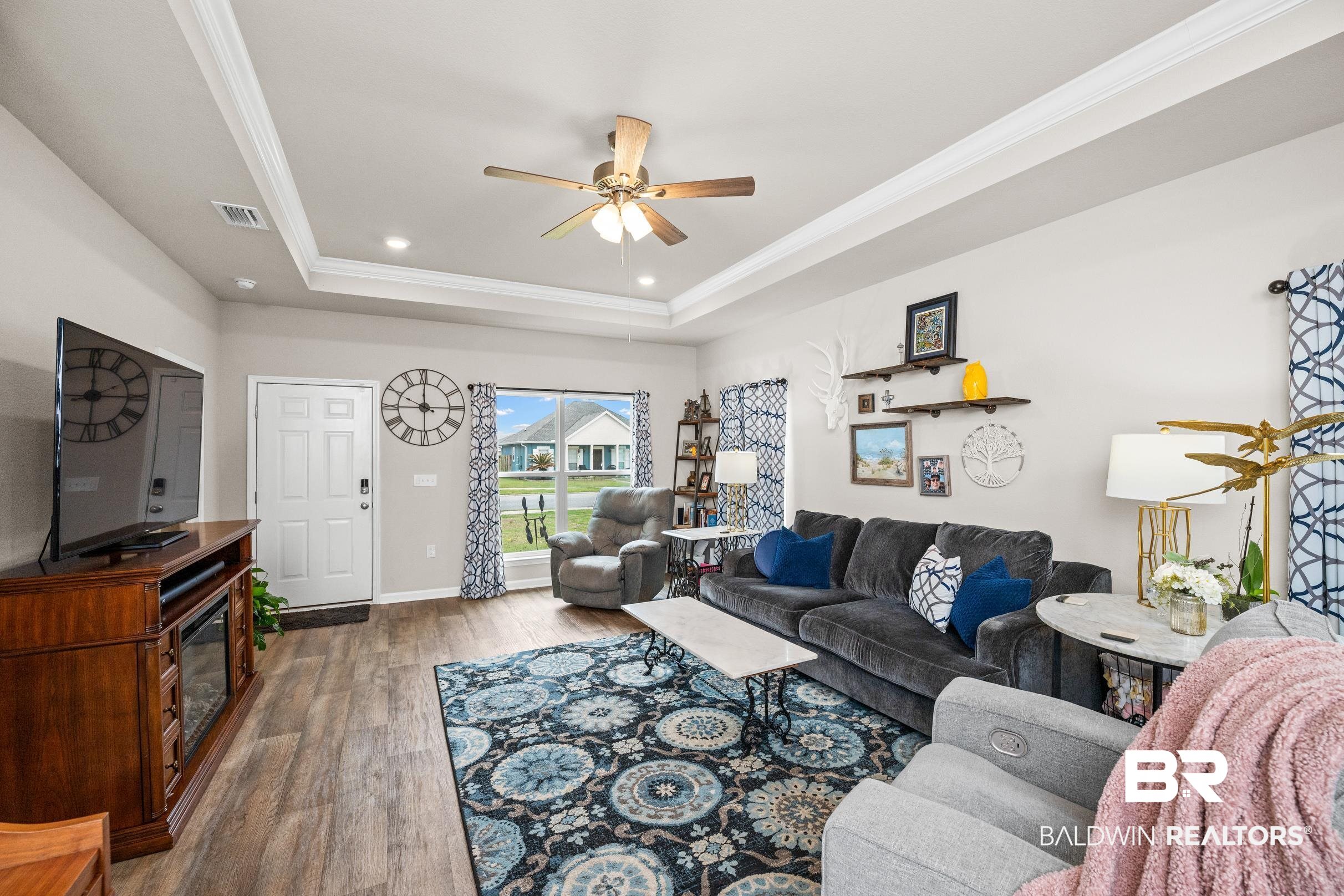 24139 Veranda Circle Elberta, AL 36530 - Photo 5 of 40 Living area featuring wood finished floors, visible vents, ceiling fan, crown molding, and a raised ceiling
