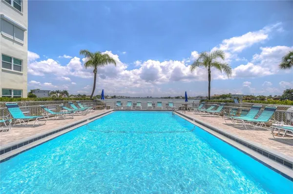 a view of a lake with couches chairs and swimming pool