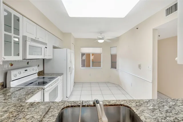 a view of a kitchen with granite countertop cabinets a sink and a chandelier