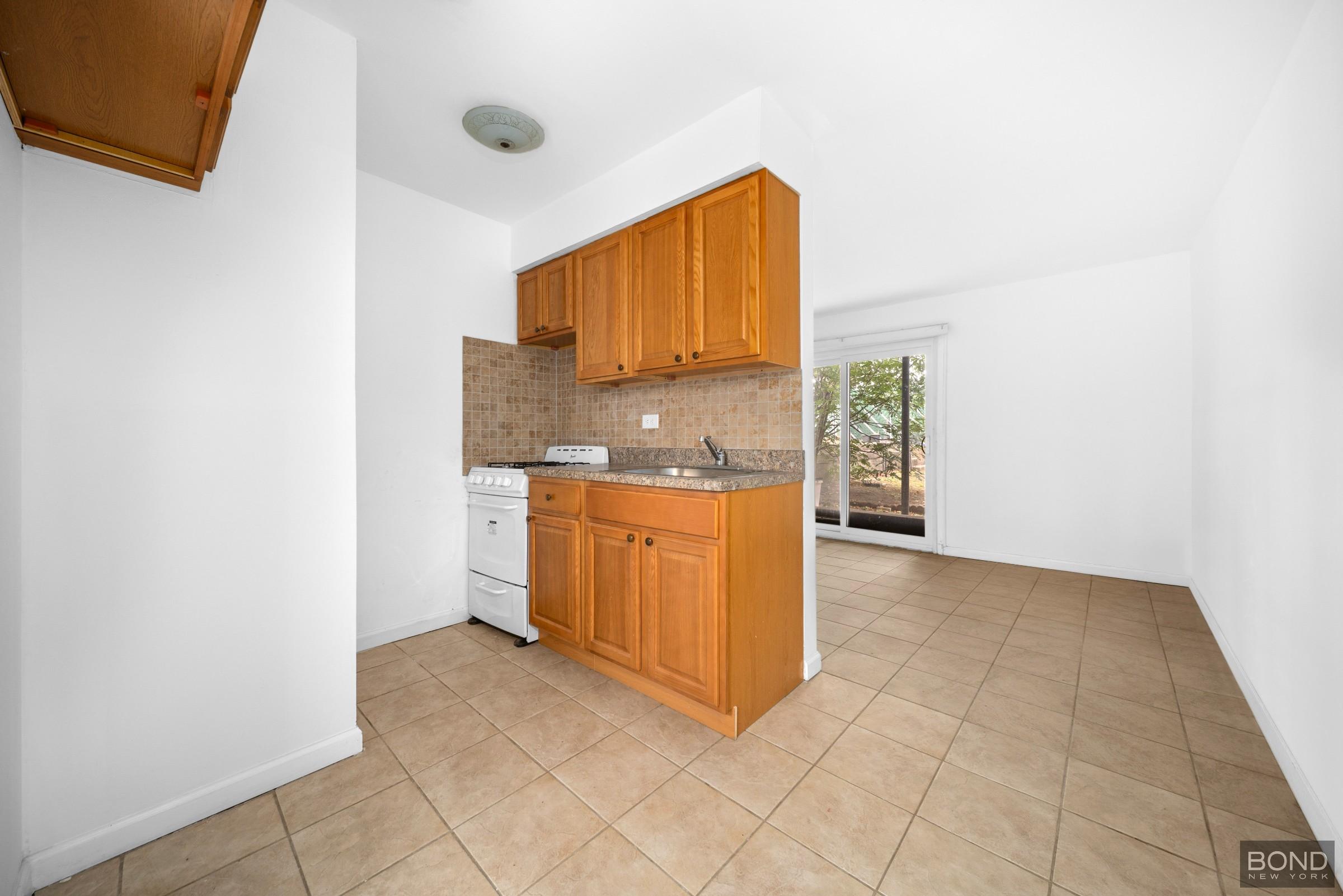 69-01 61st Road Queens, NY 11379 - Photo 8 of 9 a kitchen with a sink a stove and cabinets