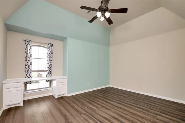 an empty room with wooden floor fan and windows