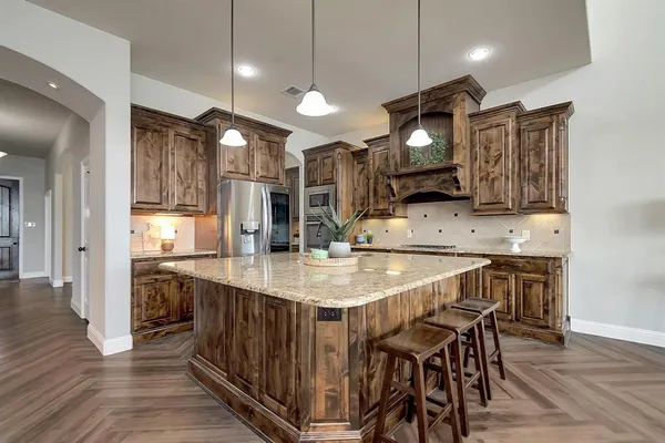 a kitchen with stainless steel appliances kitchen island granite countertop a table chairs in it and wooden floors