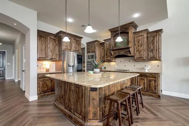 a kitchen with stainless steel appliances kitchen island granite countertop a table chairs in it and wooden floors