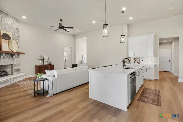 a large white kitchen with a stove and wooden floor