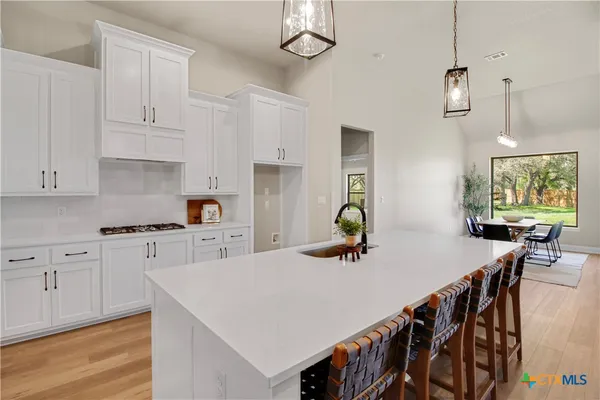 a open kitchen with stainless steel appliances granite countertop a stove a sink a refrigerator a dining table and chairs with wooden floor