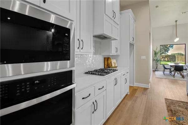 a kitchen with stainless steel appliances a stove a microwave a sink and cabinets