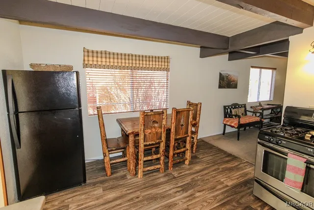 a kitchen with stainless steel appliances a refrigerator a stove a dining table and chairs with wooden floor