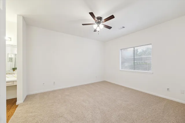 an empty room with a window and ceiling fan