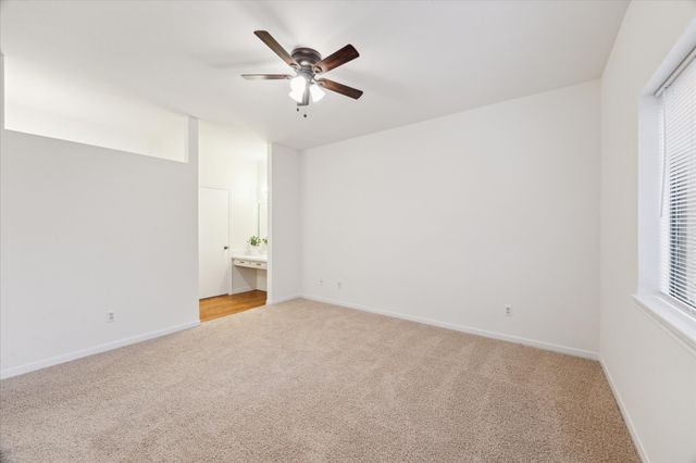 an empty room with a window and a chandelier fan