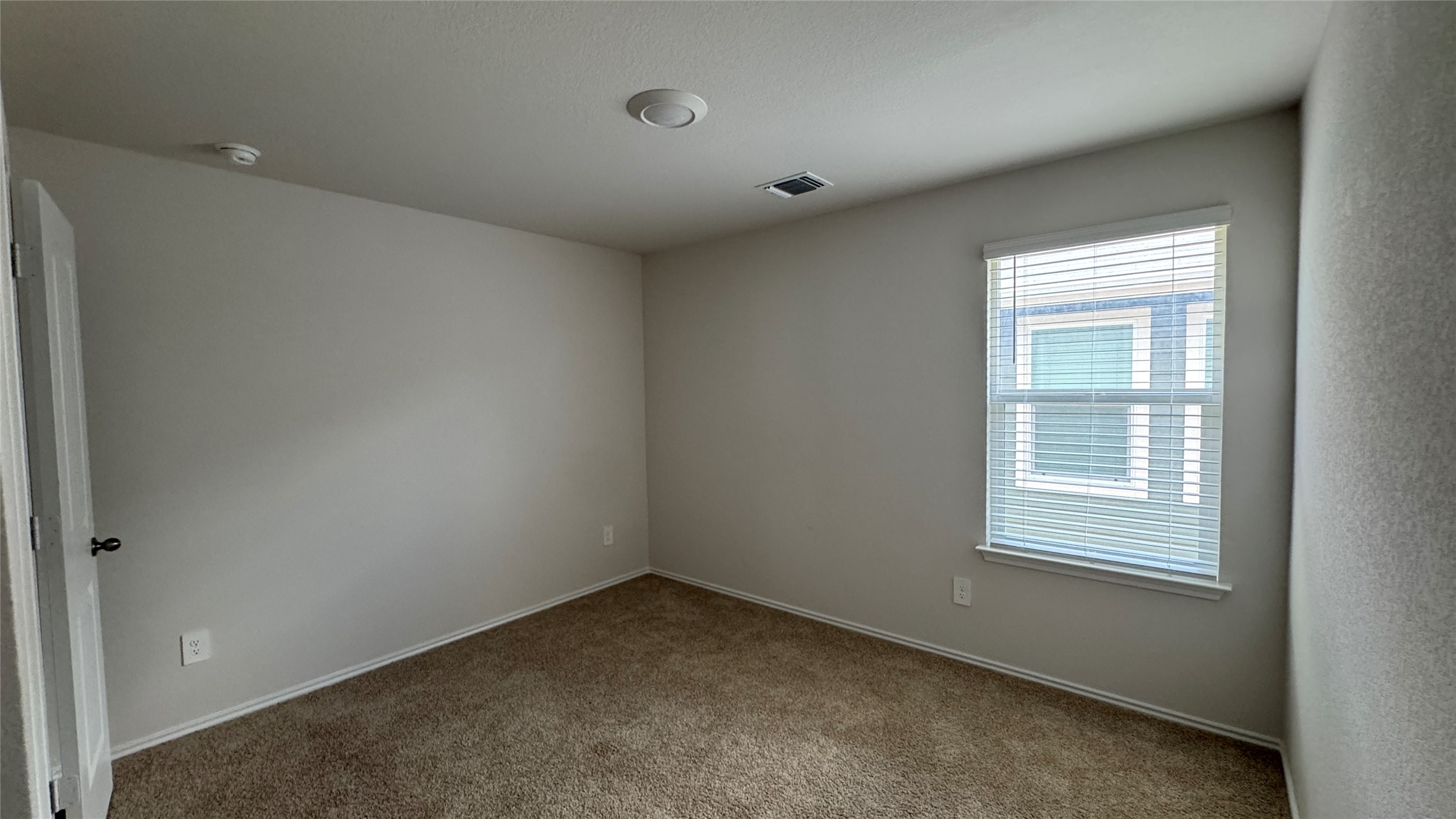 408 Frogmore Loop Kyle, TX 78640 - Photo 18 of 32 A well-lit bedroom features plush carpeting and a window with blinds, ready for personalization.