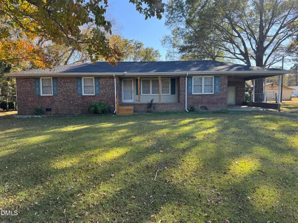 a view of a yard in front of a brick house with a large tree
