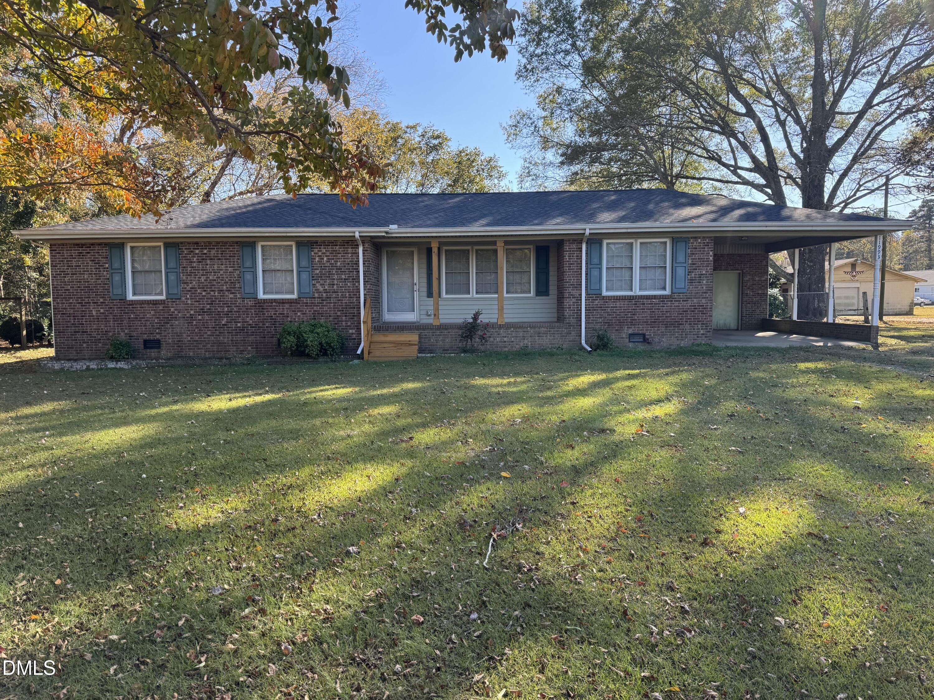 a view of a yard in front of a brick house with a large tree