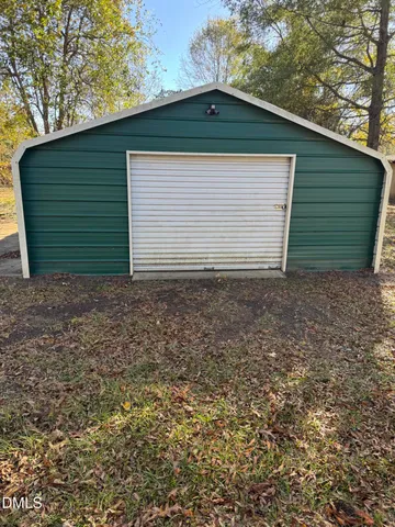 a small white house with a yard and garage