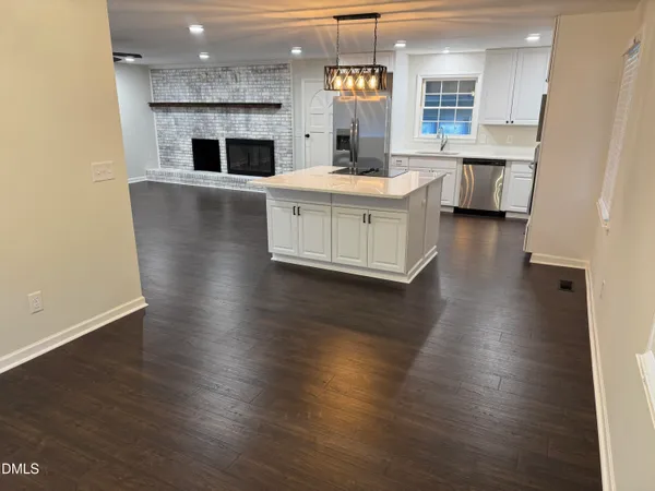 a kitchen with stainless steel appliances a white stove top oven a sink dishwasher and a fireplace with wooden floor