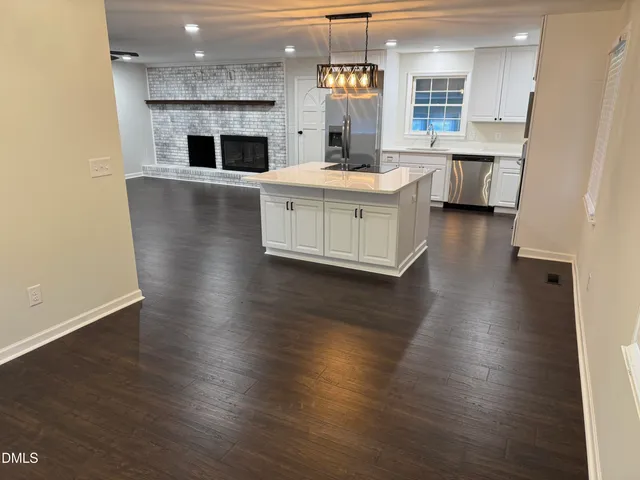 a kitchen with stainless steel appliances a white stove top oven a sink dishwasher and a fireplace with wooden floor