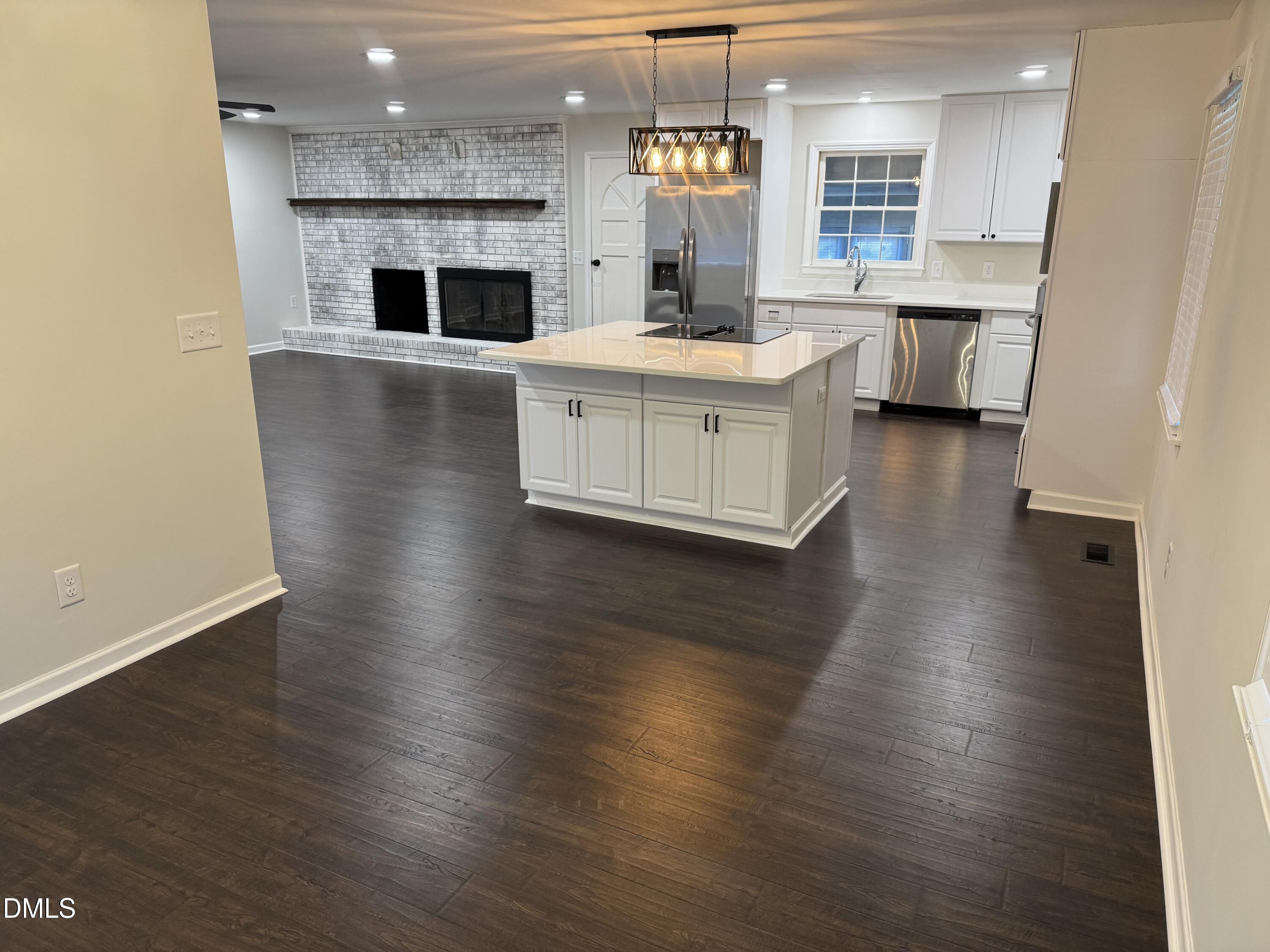11993 Rockside Road Middlesex, NC 27557 - Photo 3 of 15 a kitchen with stainless steel appliances a white stove top oven a sink dishwasher and a fireplace with wooden floor