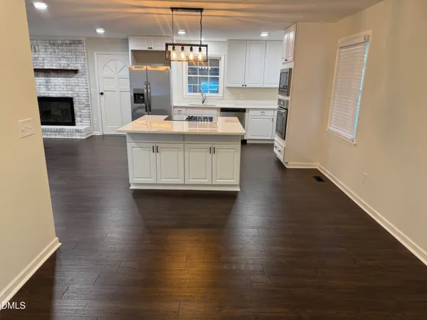 a kitchen with stainless steel appliances kitchen island granite countertop a stove a refrigerator a sink a oven and a dining table with wooden floor