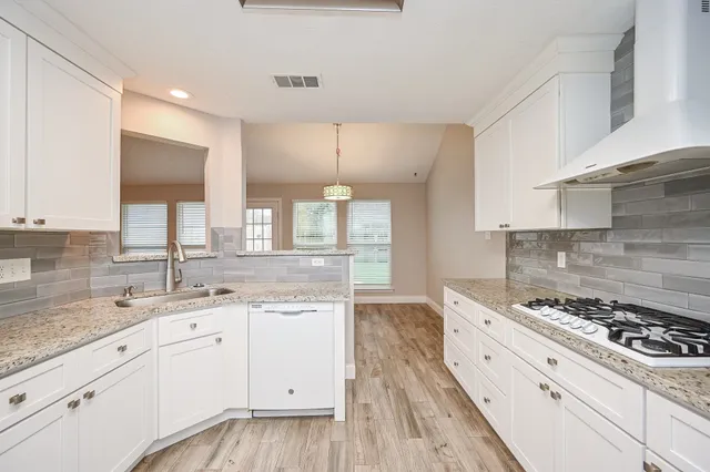 a kitchen with a stove a white cabinet and a granite counter tops