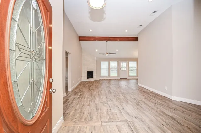 a view of empty room with wooden floor and fan